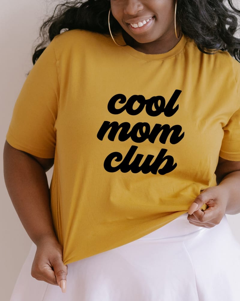 Front of a model wearing a size 2XL Cool Mom Club in Mustard by Simply Sage Market. | dia_product_style_image_id:281668